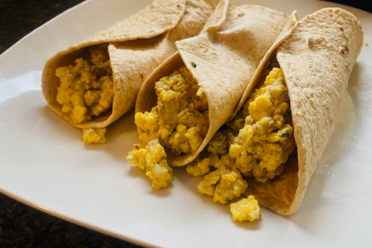 3 Cauliflower Egg Sausage And Cheese Breakfast Burrito setting on a white plate. Looks like you should try this recipe!
